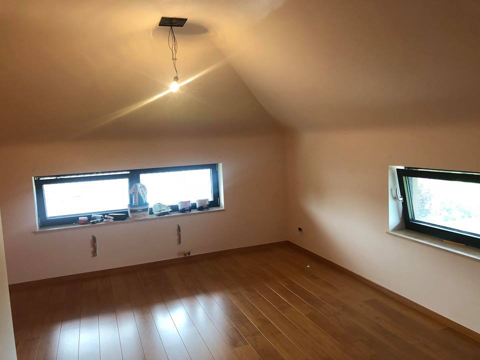 Afgewerkte zolderkamer met lichte wanden en houten vloer